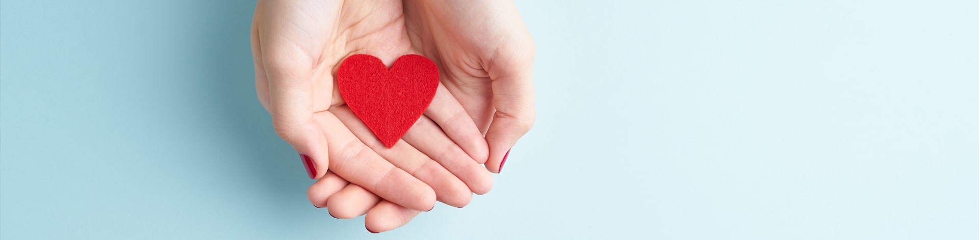 Cupped hands hold a fabric heart